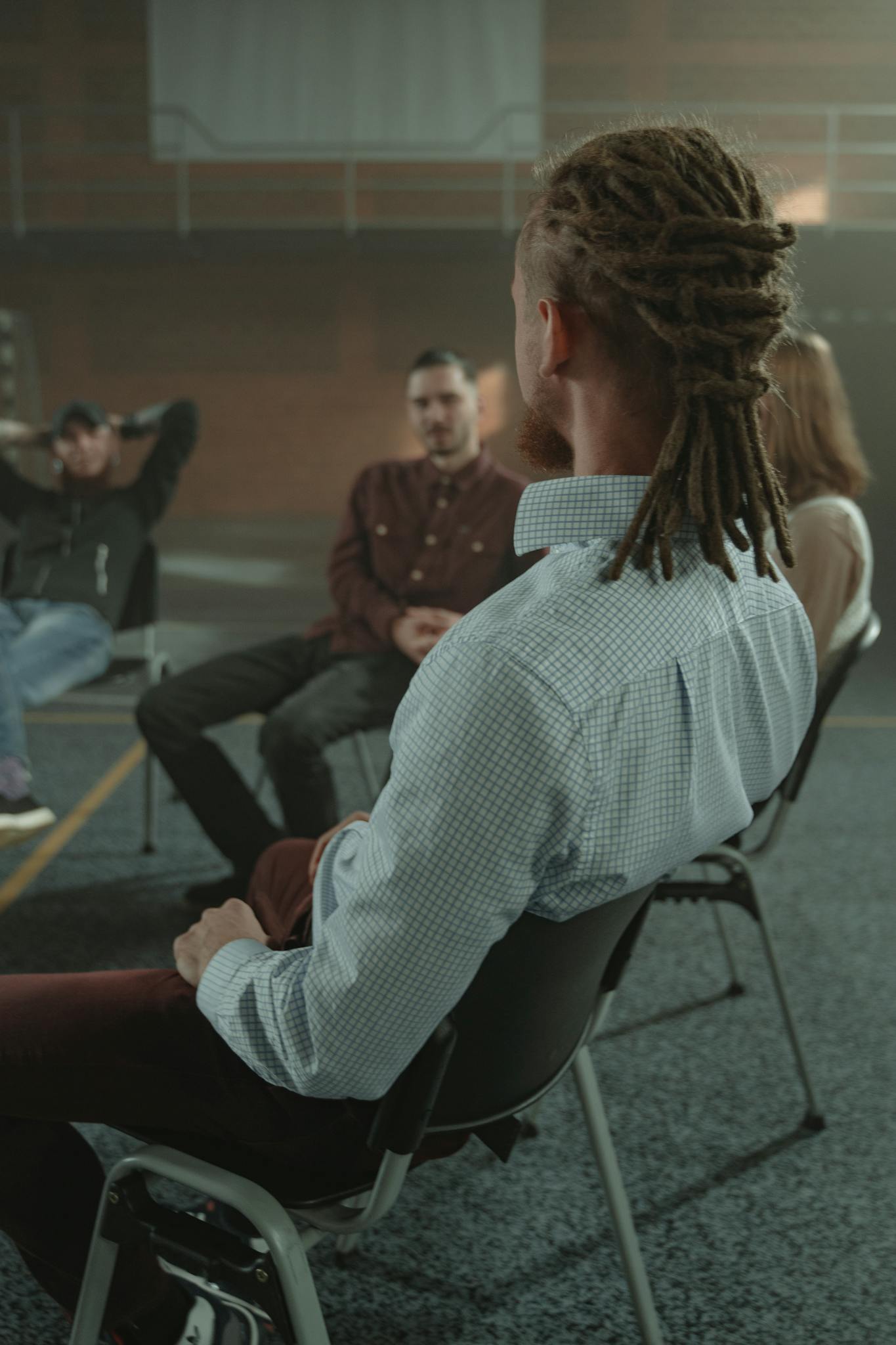A diverse group of adults engaging in a support therapy session in an indoor setting.